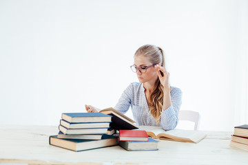 female teacher sitting at a table of many books Office
