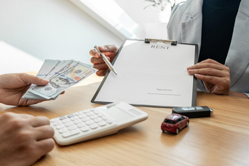 Fototapeta na wymiar Car dealership provides advice about insurance details and car rental information and delivers the keys after signing the rental contract