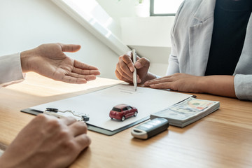 Car dealership provides advice about insurance details and car rental information and delivers the keys after signing the rental contract