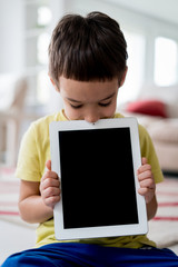 Little cute boy at home holding tablet with copy space