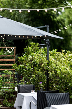 Restaurant Terrasse mit Lichterkette und schwarzem Sonnenschirm