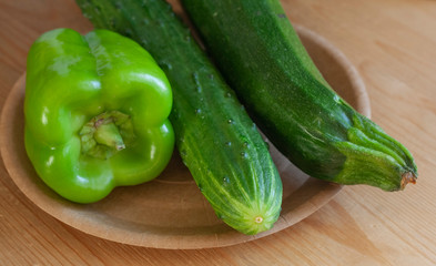 green vegetables, sweet peppers, cucumber and zucchini on paper plate on wooden table