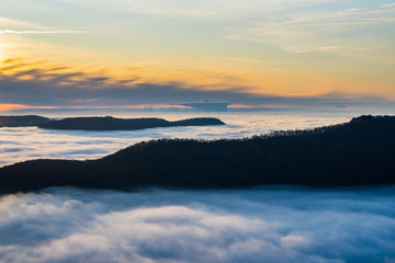 Germany, Majestic aerial view above endless fog clouds in valley of swabian jura nature landscape at sunset with orange sky near stuttgart on mountain breitenstein