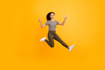 Fototapeta na wymiar Full size photo of cheerful playful girl jump relax spring free time make v-signs wear good looking clothes isolated over shine color background
