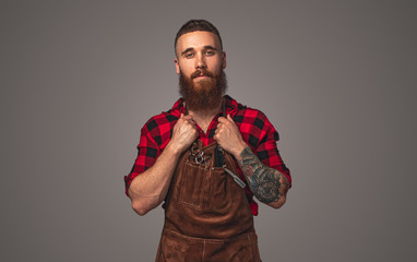 Confident bearded hairdresser adjusting apron