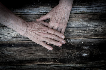 Senior hands on old wooden background