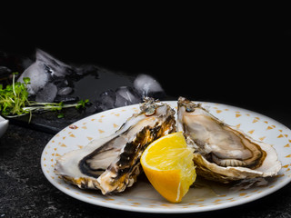 Fresh Oysters in plate, lemon, shells on marble. Delicacy super food, rich in antioxidants, vitamin, zinc