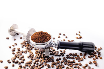 Brown roasted coffee beans and coffee powder on the potta filter isolated on white background.