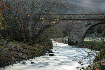 Fototapeta na wymiar Puente de piedra antiguo sobre rio en la montaña