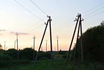 Fototapeta na wymiar poles conducting electricity in the countryside in summer at sunset