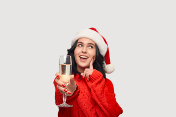 Beautiful brunette girl in a red sweater and Santa hat holding glass of champagne.