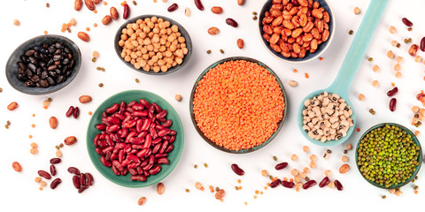 Legumes panorama, a top-down shot on a white background. Various pulses. Black and red kidney beans, lentils, soybeans, chickpeas, a flatlay