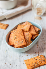 Cracker with lentil flour and sesame seeds in a cream bowl on a wooden table. Vegan food