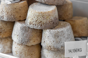 Whole cheese heads and slices in the background. French traditional cheese.