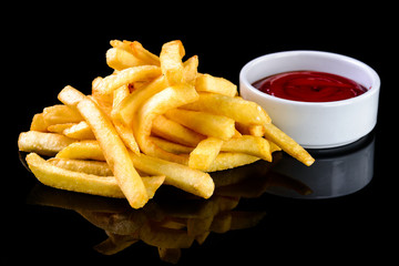 french fries and ketchup sauce in a bowl on a black background