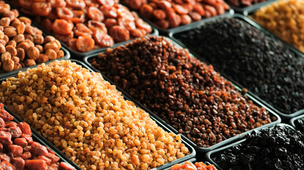 A pile of raisins, various types of dried fruits and other organic products on the counter of the store.