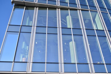 Modern office building wall made of steel and glass with blue sky