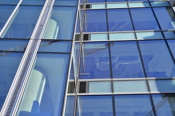 Obraz premium Modern office building wall made of steel and glass with blue sky