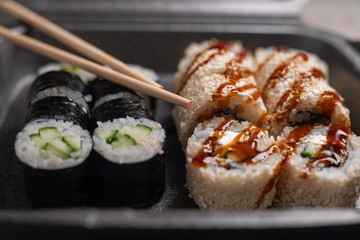 Set of assorted sushi kept in black delivery box service, selective focus