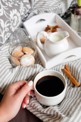 hand with a cup of coffee cozy flat lay in scandinavian style. Coffee with cookies in bed.