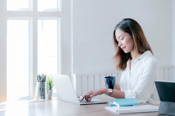 Portrait of young businesswoman working with laptop  while sitting at office desk in modern office.