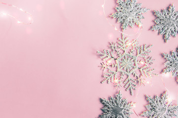 Christmas decor snowflakes with garland on pink background. Copy space.