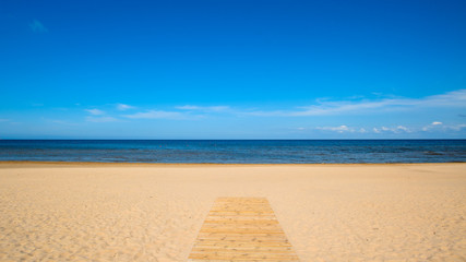 Fototapeta na wymiar Wooden walkway leading to the sandy beach of Baltic Sea, Latvia, Europe