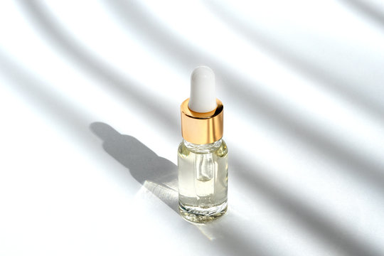Anti aging serum with collagen and peptides in glass bottle with dropper on white background with shadows. Anti-age product, luxury body care and organic science concept. Dropper glass bottle mock-up.