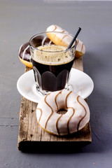 Glass of Black Americano Coffee and Tasty Chocolate and Vanilla Donuts on Wooden Tray Gray Background Morning Breakfast Lifestyle Vertical