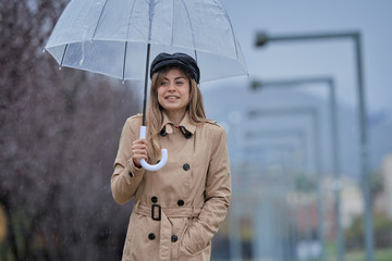 a girl walking through a park, with a transparent umbrella because it rains