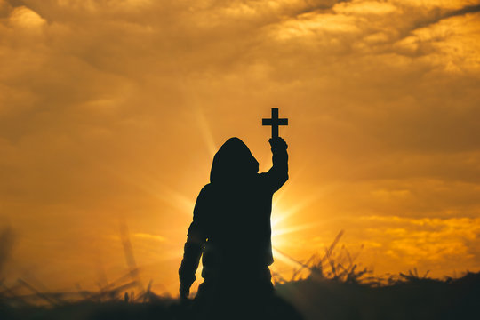 Man raise the cross to sky for praying to God at sunset background. christian silhouette concept.