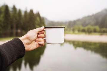 Mug with coffe in traveler's hand.