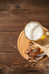 Beer glass with beer and hot smoked fish close-up. Beer mug with beer and fish on a dark background and copy space.