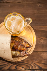 Beer glass with beer and hot smoked fish close-up. Beer mug with beer and fish on a dark background and copy space.