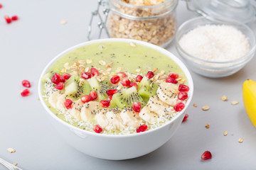 Healthy breakfast detox green smoothie with banana, kiwi, spinach, chia and pomegranate seed in a Bowl. Vegan food.