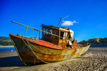 Rusty abandoned ship ashore at low tide.