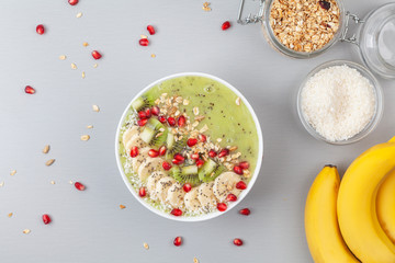 Healthy breakfast detox green smoothie with banana, kiwi, spinach, chia and pomegranate seed in a Bowl. Vegan food. Top view.