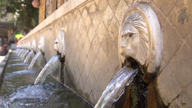 This is a static shot of a lion head fountain with water flowing,