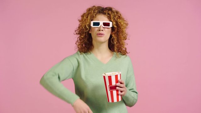 dissatisfied woman throwing popcorn isolated on pink