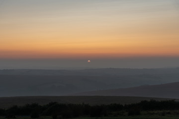 the red and orange sky at sunset over a hazy Exmoor