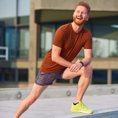 Fototapeta premium Young man exercising / stretching in urban park.