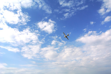 A plane flies in blue sky among the clouds