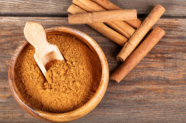 Cinnamon sticks and cinnamon powder on wood