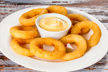 Squid rings with sauce on a white plate shot horizontally