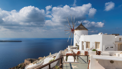Romantic view of Greek windmill with white buildings and Mediterranean sea in Oia town, Santorini...