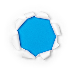 Paper hole in white paper with ragged edges with blue background.