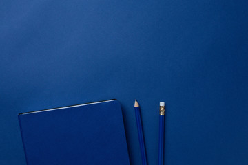 Blue office notebook and pencil on a classic blue background. Trendy color 2020
