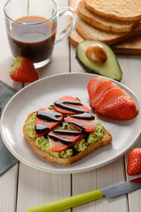 Toast with avocado, strawberries, chocolate and cup of coffee