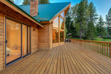 Luxury summer mountain cabin home with large wooden porch and bedroom view.