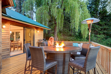 Luxury summer evening mountain home eteriors with cozy porch fire table and new furniture design.